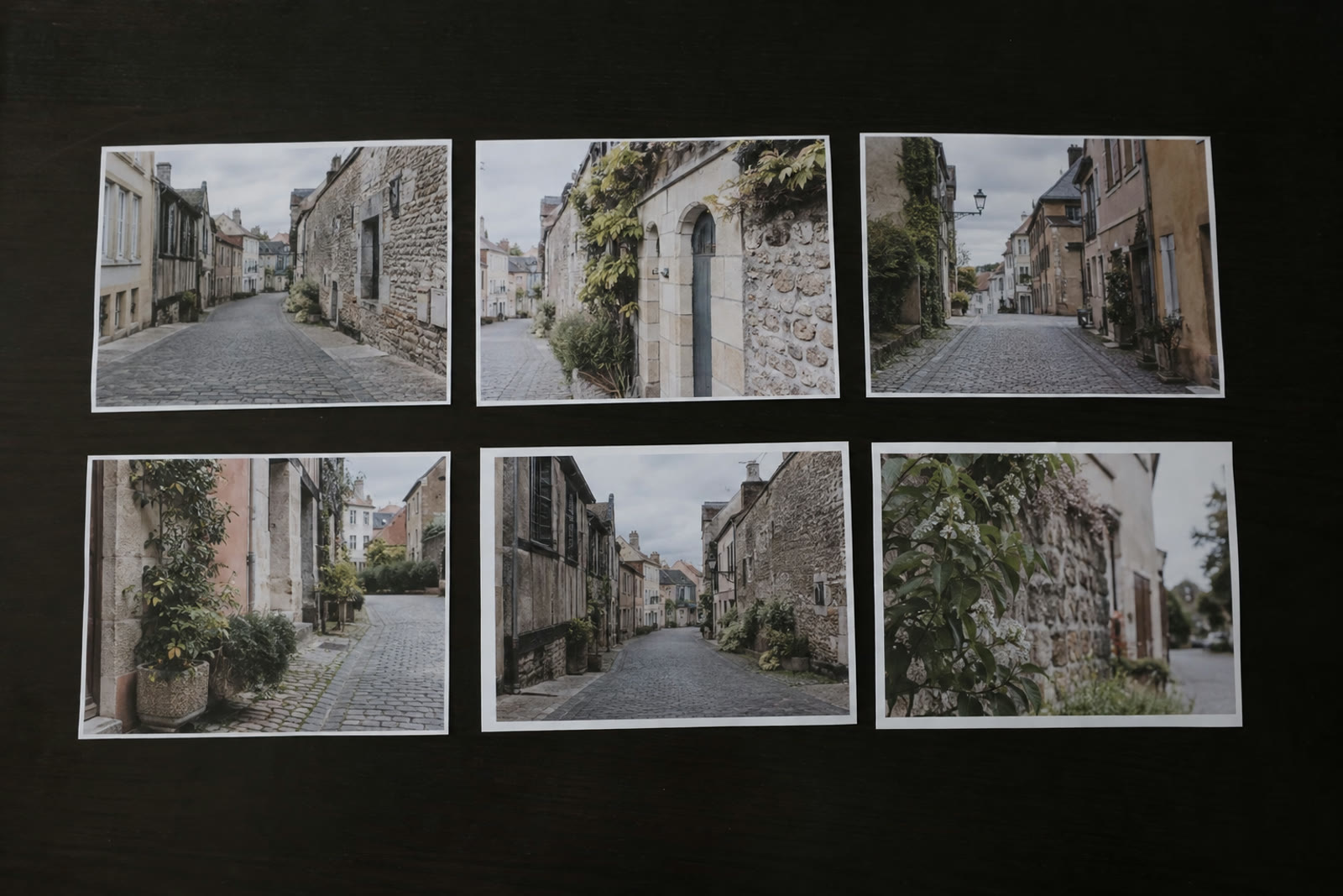 A row of small photo prints of the same street from different angles laid out on a table
